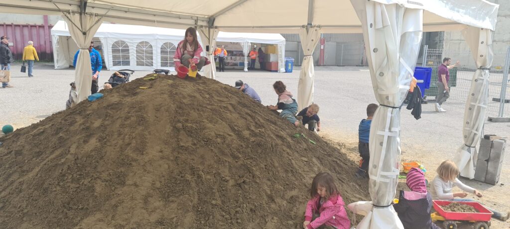 Kinder spielen auf einem Sandberg.